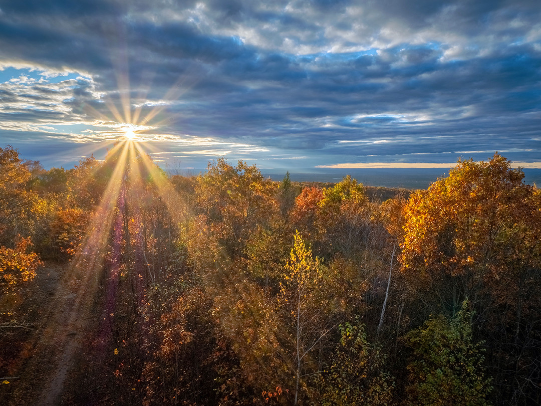 The sun’s rays break through layered clouds before fading into an autumn evening in Connecticut.⁠
⁠
I took this photograph during the peak to late fall transition last year, in northern Connecticut. I knew the cloud cover on this evening was quite promising in terms of sunset potential, but when I got to this location, it became clear that the sunset was either going to be completely amazing or completely blocked out, due to the extensive stratocumulus cloud deck.⁠
⁠
Ultimately, the sunset was completely blocked. But, for just a brief moment, the sun was visible through a gap in the clouds before being completely blanketed from that point on, allowing me to take this one photograph.