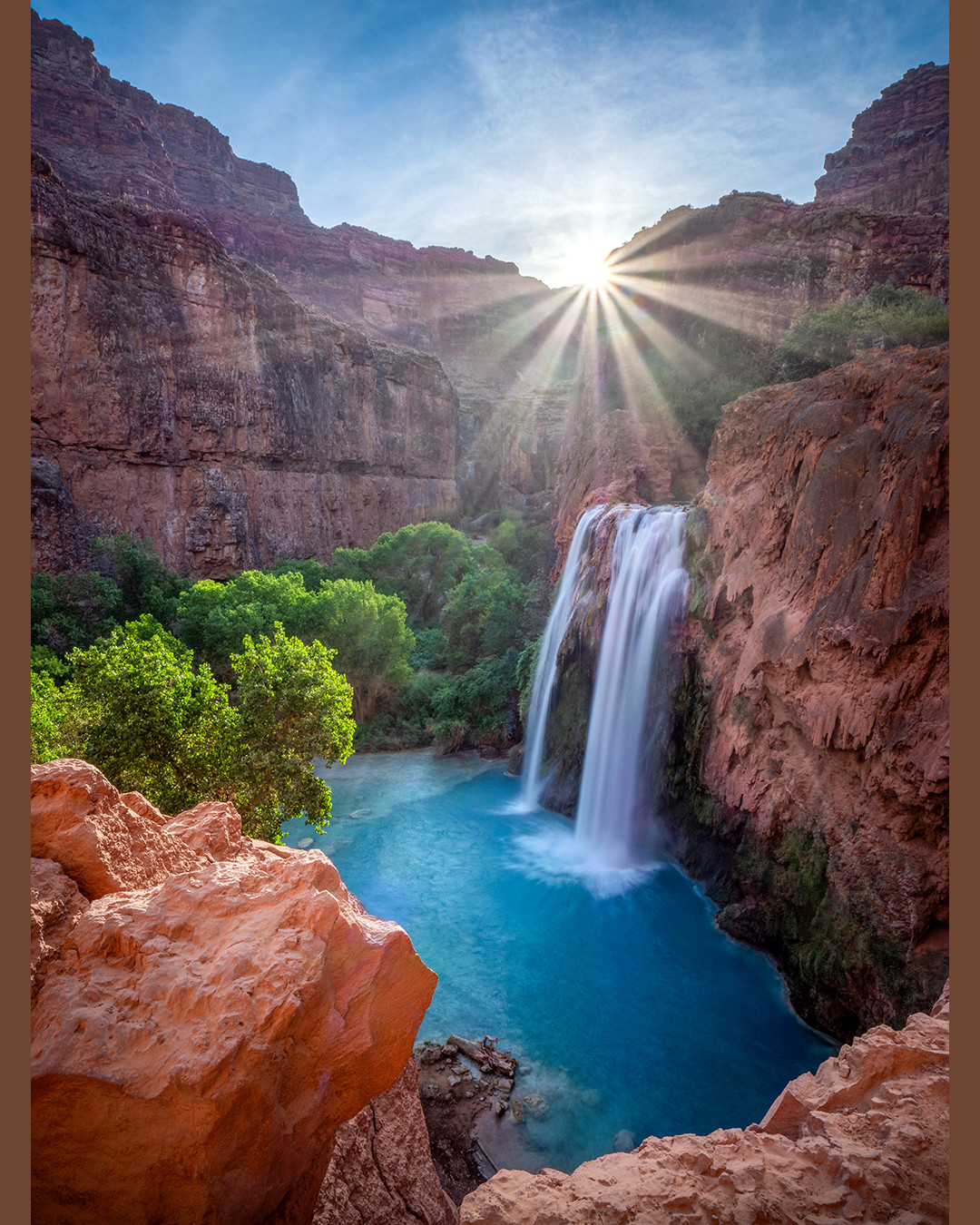 Havasu Falls drops into the turquoise waters of the travertine pool below as the sun rises above the canyon walls.⁠
⁠
Havasu Falls is the most well-known waterfall within the Havasupai Indian Reservation in Arizona, with four other major waterfalls found along Havasu Creek. Besides dropping an impressive 100 feet (30 m), the vivid turquoise color of the water is the real showstopper here. This color comes from high concentrations of dissolved calcium carbonate and magnesium. As these minerals precipitate out of the water, they form travertine, a type of limestone that is continuously reshaping the waterfalls, pools, and terraces throughout Havasu Creek.⁠
⁠
Having recently spent three days at the Havasupai Campground, I was able to photograph Mooney, Beaver, Hidden, Fifty Foot, and Havasu Falls. I captured a variety of images that I will certainly share in the future. This particular photograph was taken shortly after sunrise on my first morning in the canyon. I waited for the sun to rise above the canyon walls, allowing a sunstar to form while illuminating the vivid green vegetation, red sandstone cliffs, and brilliant blue water below.