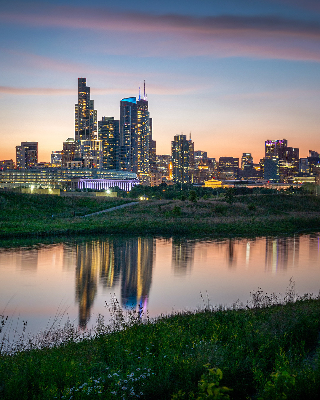 The Chicago skyline starts to glow as day turns to night, as seen from Northerly Island Park.⁠
⁠
I posted a photo from this exact area about two months ago, taken roughly 15 minutes before this one and only about 50 feet away. Chicago has one of the most beautiful skylines in the world, and there is no shortage of picturesque vantage points from which to appreciate it. What makes the view from Northerly Island Park unique is the combination of the natural elements found throughout this 100-acre park with the urban skyline rising behind them.⁠
⁠
The stillness of the 5-acre lagoon in the middle of the park created a perfect opportunity to reflect the last colors of daylight as the lights of the Chicago skyline began to come to life.